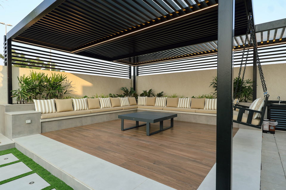 A slatted pergola sheltering a built-in majlis with cushioned seating, project A49 in Ajman
